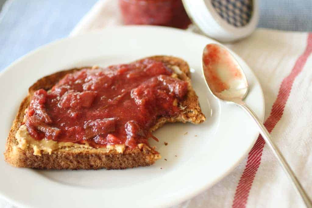 Strawberry Rhubarb Ginger Jam on toast on a white plate with a spoon of jam