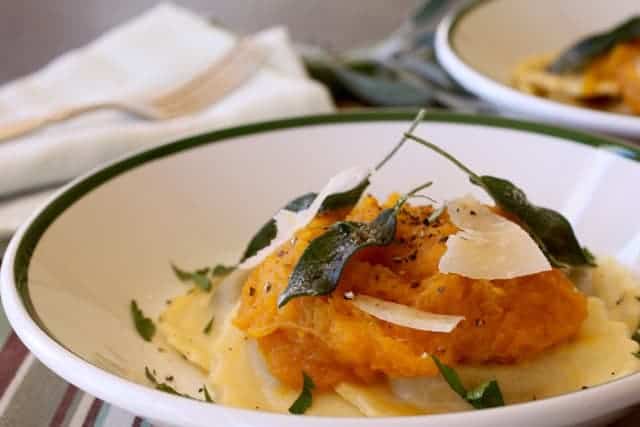 Bowl of packaged of refrigerated mushroom ravioli topped with cooked squash and a sage-infused brown butter