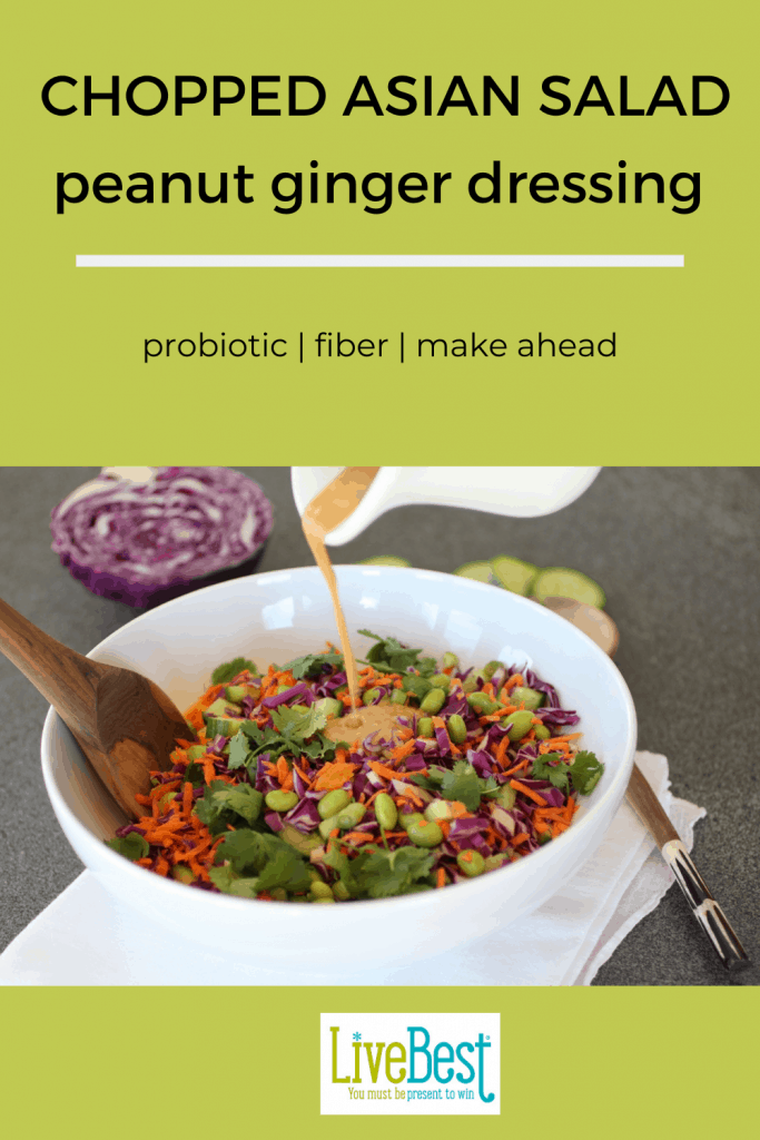 bowl of chopped asian salad with peanut ginger dressing being poured over top