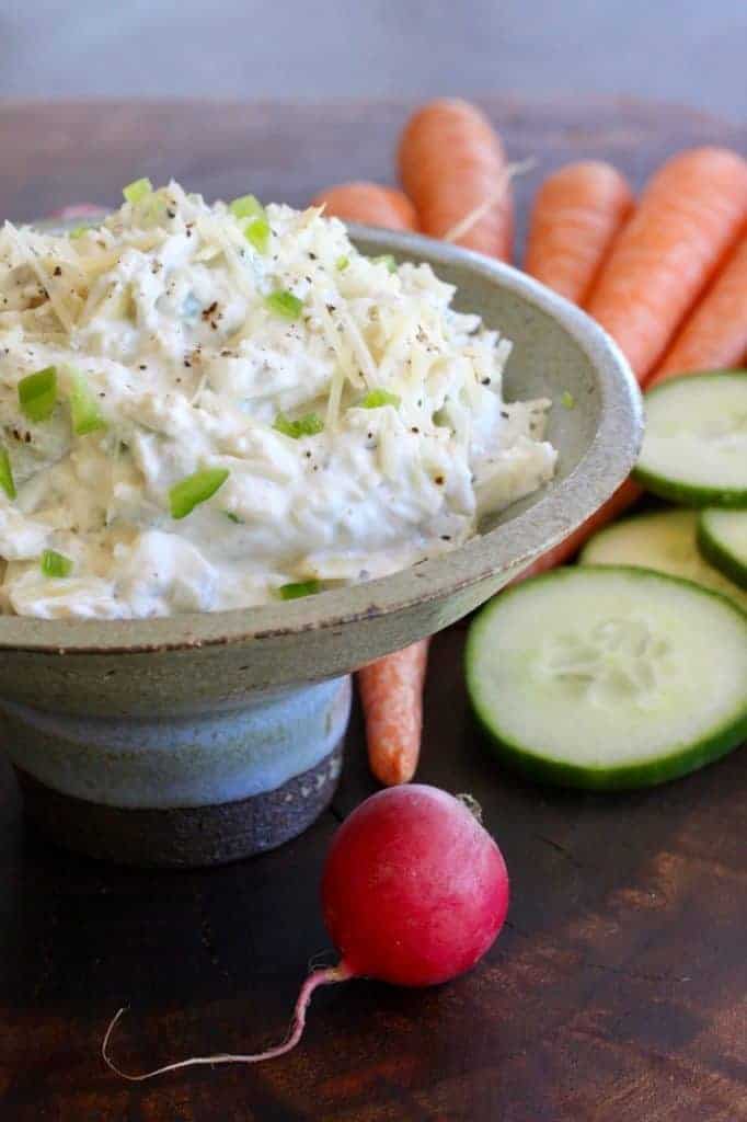 Artichoke Jalapeño Dip in bowl with radish and cucumber