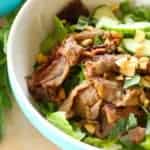 bowl with beef, peanuts, lettuce, cucumbers, basil and rice noodles