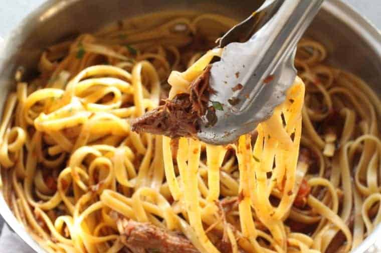 Short Rib Ragu with pasta lifted with tongs