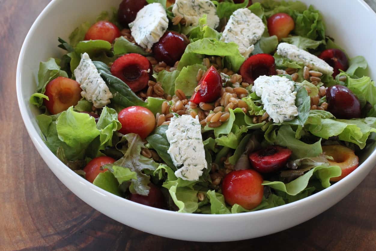 bowl of salad with cherries, spelt and goat cheese