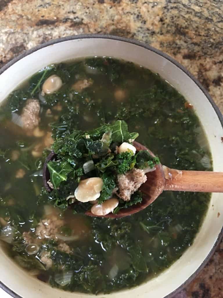 a pot of turkey kale bean soup with a spoon