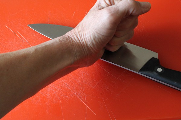 hand and knife smashing a garlic clove