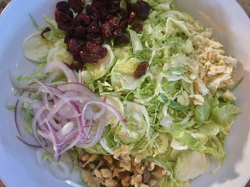 image of Brussels sprouts salad ingredients dried cranberries, red onion, toasted walnuts