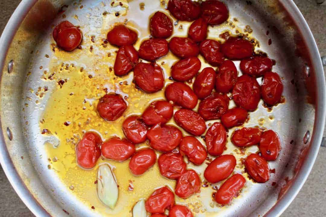 pan of cooked grape tomatoes with garlic and olive oil