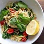a bowl of spaghetti with spinach, blistered tomatoes and pine nuts