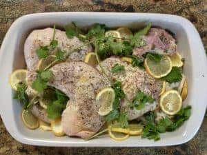 chicken thighs in pan with lemon, capers and spices ready to bake