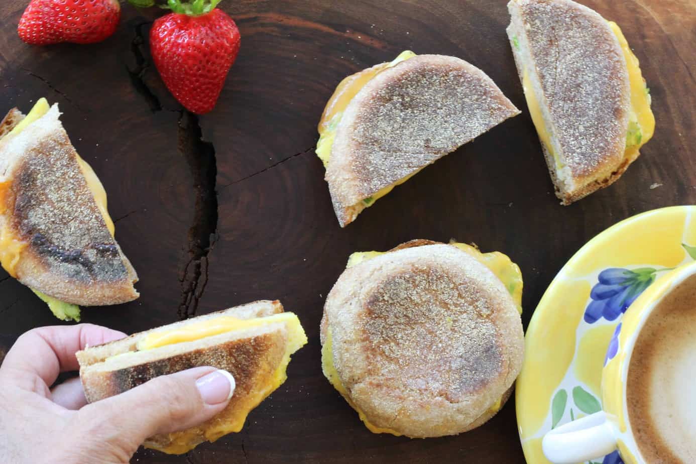 English muffin egg and cheese breakfast sandwiches on a board.