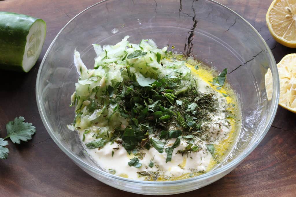 a bowl of yogurt, cucumber and herbs 