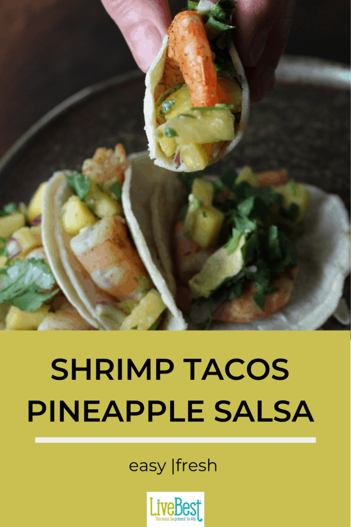 a hand holding a shrimp tacos with pineapple salsa