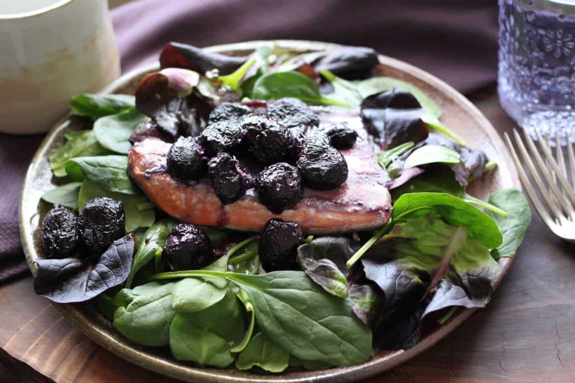 salmon fillet with caramelized grapes on fresh spinach