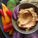 Bowl of hummus with fresh peppers and cucumber slices