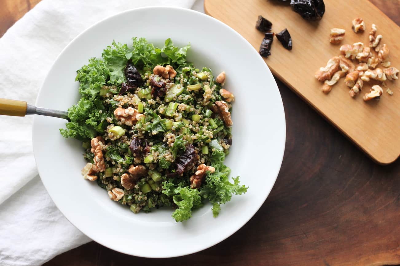 bowl of kale quinoa salad with walnuts and chopped prunes