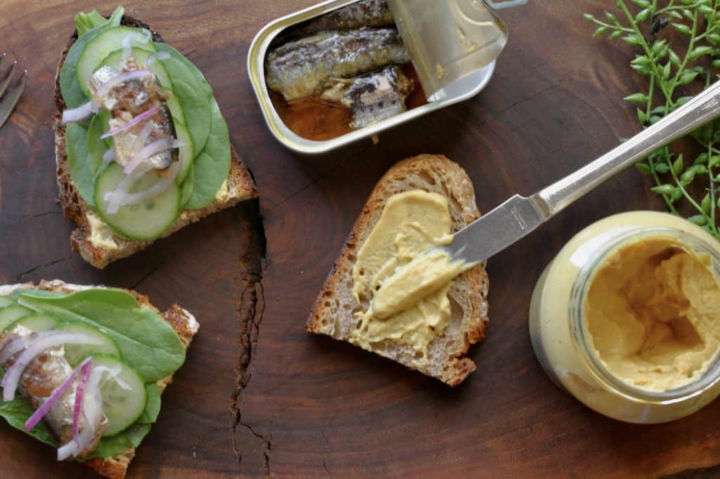 slices of bread with spinach leaves, cucumber slices and sardines with mustard