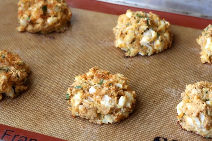 six baked crab cakes on a baking sheet pan