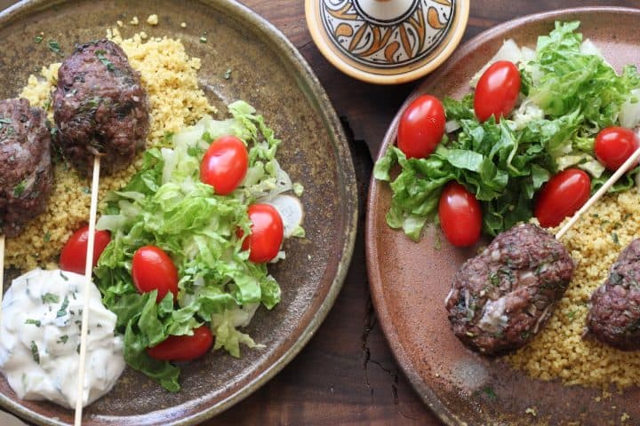 ground beef kebabs with lettuce, tomato and rice on plates