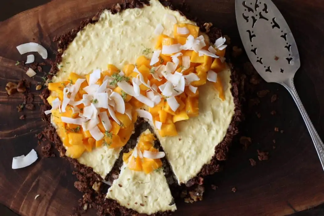 baked yogurt tart topped with fresh mango and coconut tart with a slice cut away