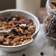 bowl of lemon blueberry granola with a spoon and milk. in the background