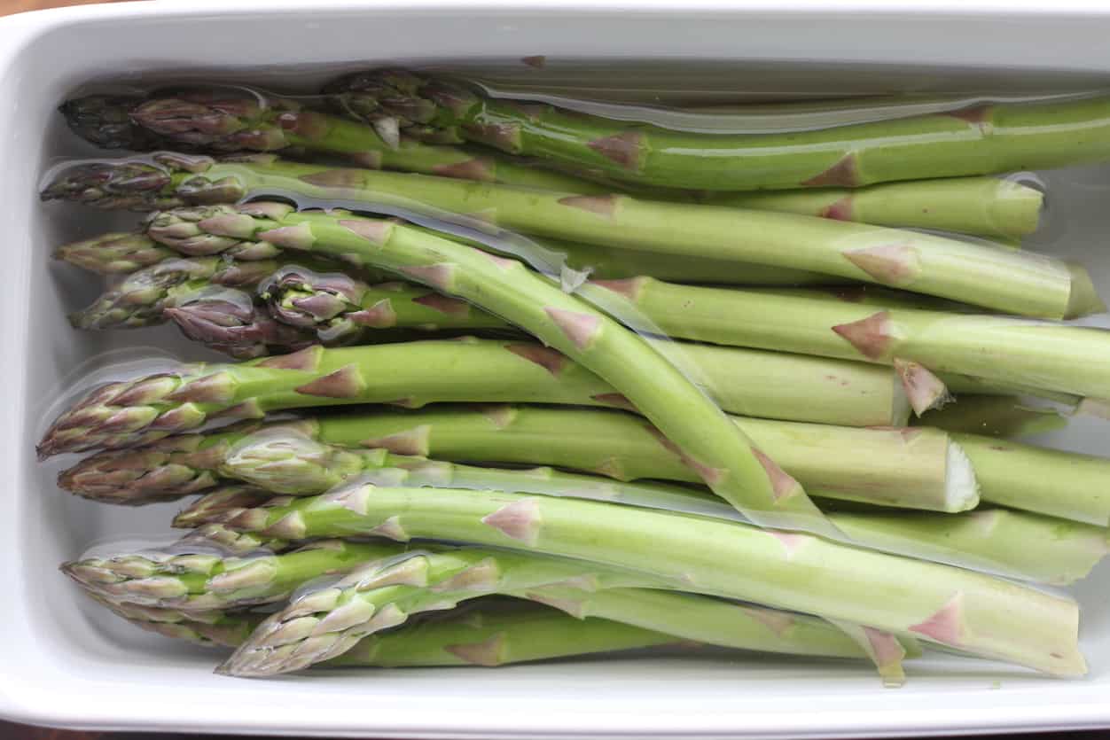 asparagus in a loaf pan filled with water