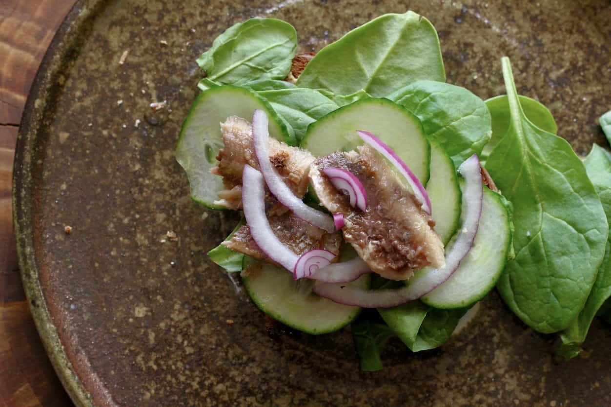 sardine sandwich with sliced cucumber and red onion and arugula